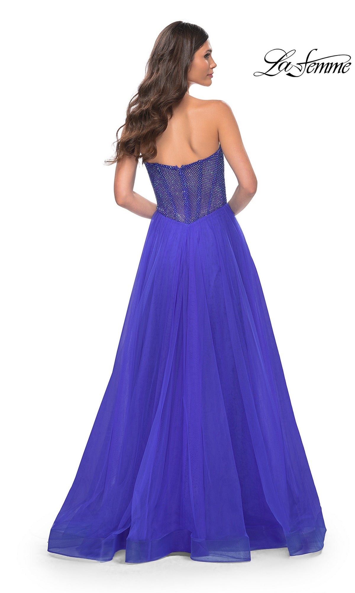 A woman faces away from the camera in the La Femme Strapless Long A-Line Prom Dress 32216, featuring a sheer corset-style back. The elegant dress and La Femme logo appear in the image.